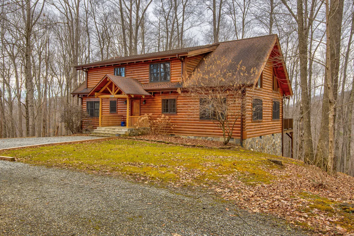 This image features the log cabin's charming exterior, set amidst tall trees with the inviting front porch and large windows visible. The scene radiates tranquility and highlights the cabin's seclusion, making it an ideal base for outdoor adventures. The wooded surroundings reinforce the sense of privacy and connection to nature.