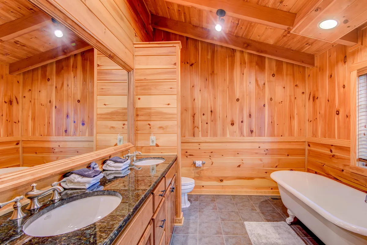 A modern bathroom with a soaking bathtub, a vanity with dual sinks, and large mirrors. Soft, warm lighting enhances the sense of tranquility, making the space inviting for relaxation and self-care routines.